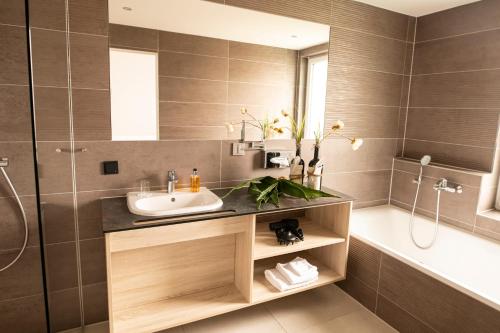 a bathroom with a sink and a shower and a tub at Hotel Campo in Renningen