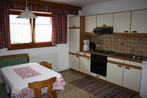 eine kleine Küche mit einem Tisch und einem Herd Top-Backofen in der Unterkunft Haus Ampferstein in Telfes im Stubai