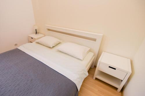 a small bedroom with a bed and a night stand at Old Town Apartments in Alytus