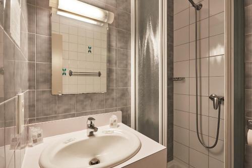 y baño con lavabo y ducha. en Cit'Hôtel Le National en Cluses