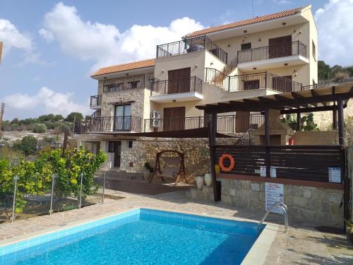 a villa with a swimming pool in front of a house at Kalypso View Apartments in Letimbou