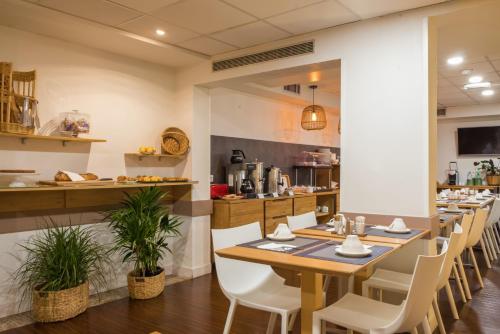 a restaurant with a long table and white chairs at Hotel Le Richemont in Paris