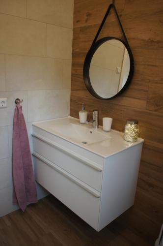 ein Badezimmer mit einem weißen Waschbecken und einem Spiegel in der Unterkunft Áshóll guesthouse - farmstay in Akureyri