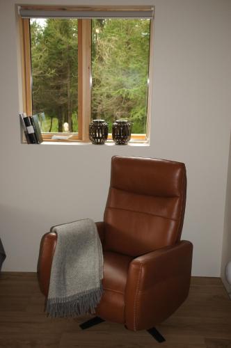 a brown leather chair sitting in front of a window at Áshóll guesthouse - farmstay in Akureyri