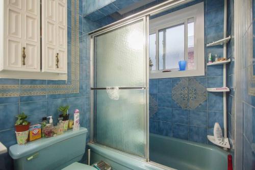 a blue tiled bathroom with a shower and a toilet at Freeda's Place in Toronto