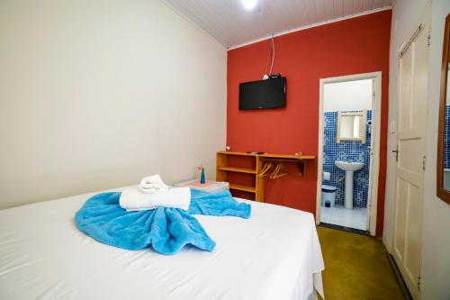 a bedroom with a white bed and a red wall at Pousada Sunset Boipeba in Ilha de Boipeba