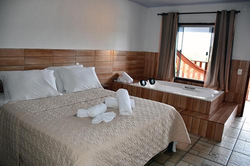 a bedroom with a large bed and a bath tub at Pousada Estrela Guia in Pirenópolis