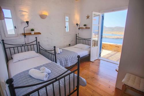 two beds in a room with a view of the ocean at Antiparos Vibes in Agios Georgios