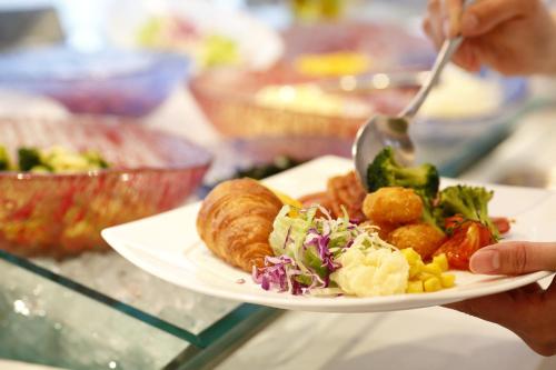 a person holding a plate of food with a spoon at ANA Crowne Plaza Chitose by IHG in Chitose