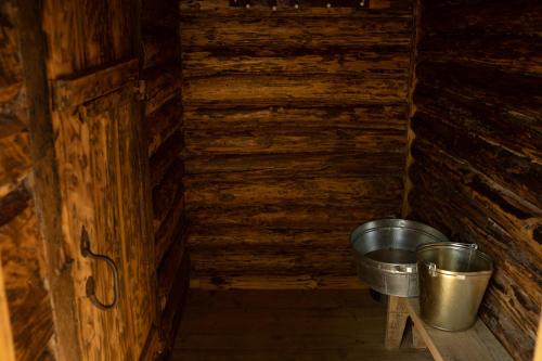 a small room with a bucket in a log cabin at Viesu nams Melnsils in Melnsils
