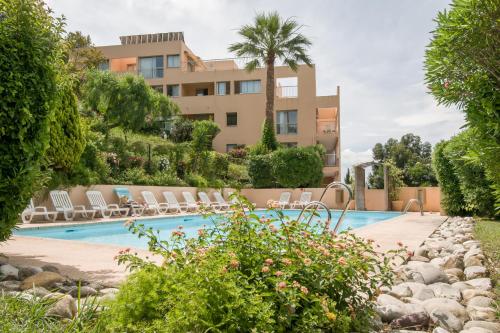 un complexe avec une piscine entourée de chaises et un bâtiment dans l'établissement Résidence Villa Livia, à Cannes