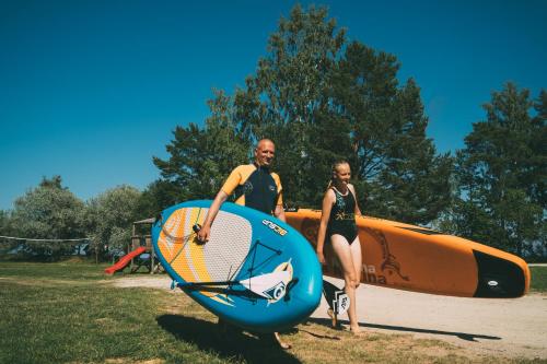 a man and a woman standing next to a surfboard at Viesu nams Melnsils in Melnsils