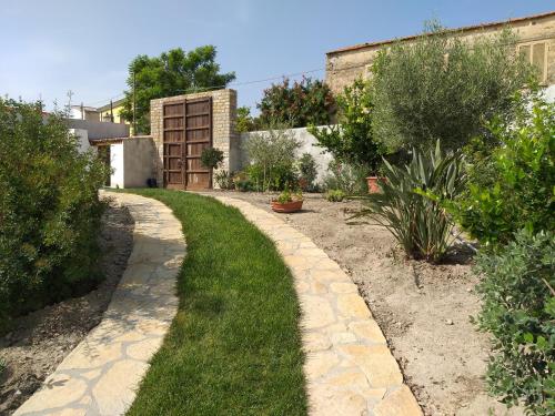 a garden with a walkway with grass and bushes at L'Antica Dimora - Suites & Apartments in Màndas