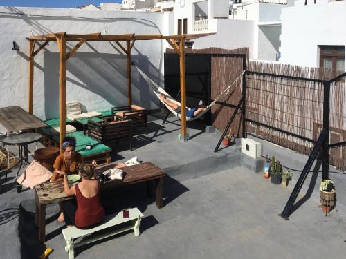 two people sitting on a patio with a hammock at Casa Calma Yoga Hostel in Agaete