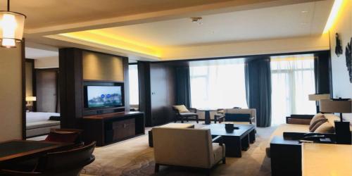 a living room with a couch and a tv at Howard Johnson Neodalle Resort Zhangjiajie in Zhangjiajie