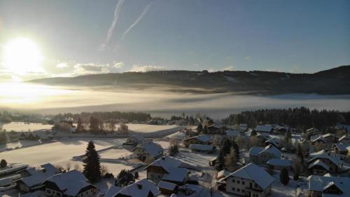 a village covered in snow with the sun in the background at Panoramahaus Steiner in Mariapfarr