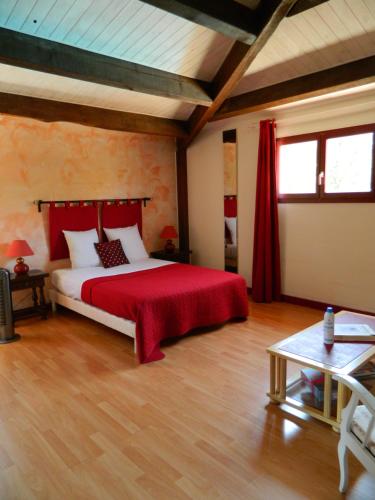 um quarto com uma cama grande e um cobertor vermelho em le clos des dryades f em Vers