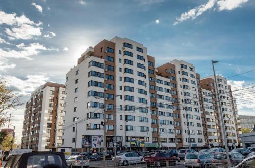 a large white building with cars parked in a parking lot at Luxury Apartments Newton by GLAM in Iaşi