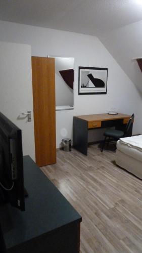 ein Wohnzimmer mit einem Bett und einem Schreibtisch mit einem TV in der Unterkunft Zur Mühle in Bocholt