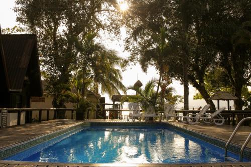 a swimming pool with chairs and a table and trees at Chalés do Laurindo in Maciel