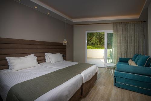 a bedroom with a large bed and a blue couch at Alexandra Beach Resort & Spa in Tsilivi
