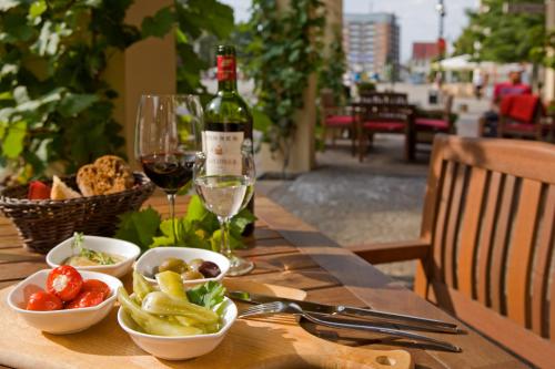 a table with a bottle of wine and bowls of food at Vienna House by Wyndham Sonne Rostock in Rostock