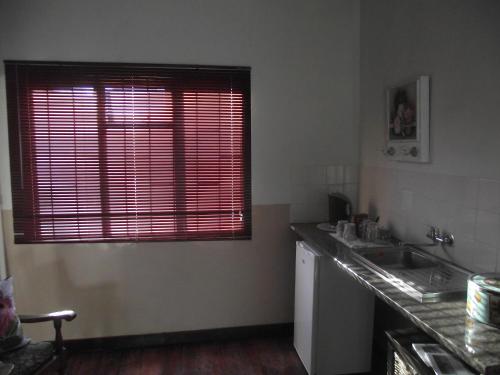 a kitchen with a sink and a window with red blinds at Lavender Rose in Bethulie