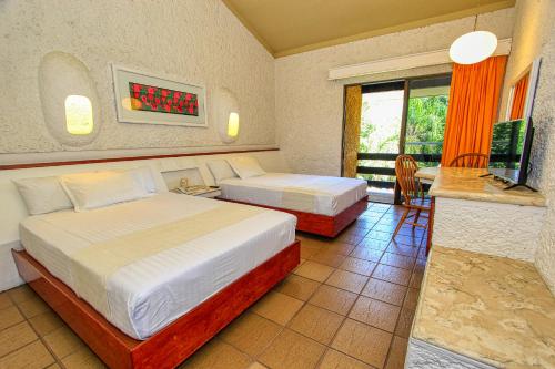 a hotel room with two beds and a balcony at Hotel Ciudad Real Palenque in Palenque