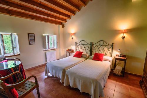 Un dormitorio con una cama con almohadas rojas. en Hotel Rural La Casa del Burrero, en Castropol