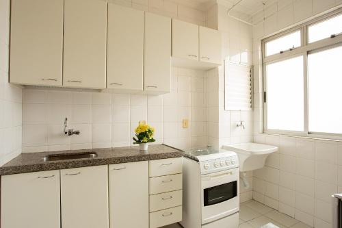 a white kitchen with white cabinets and a sink at Pampulha Flat in Belo Horizonte