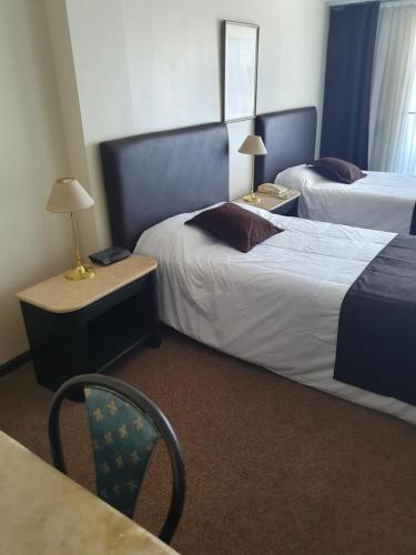 a hotel room with two beds and a table and a chair at Departamento Céntrico in Rosario