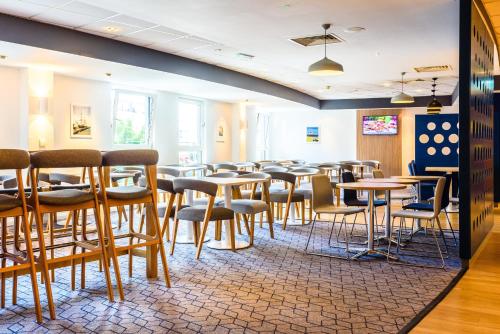 a dining room with tables and stools at Holiday Inn Express Portsmouth Gunwharf Quays by IHG in Portsmouth