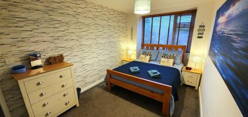 een slaapkamer met een blauw bed en een bakstenen muur bij Palm Court in Bournemouth
