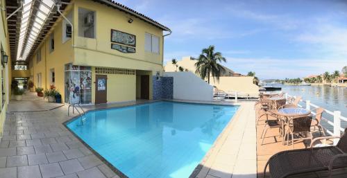 a swimming pool next to a building with a body of water at Pousada Porto Canal in Cabo Frio