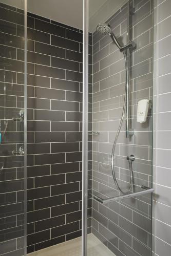 a bathroom with a shower with black tiles at Holiday Inn Express St. Albans - M25, Jct.22 in Saint Albans