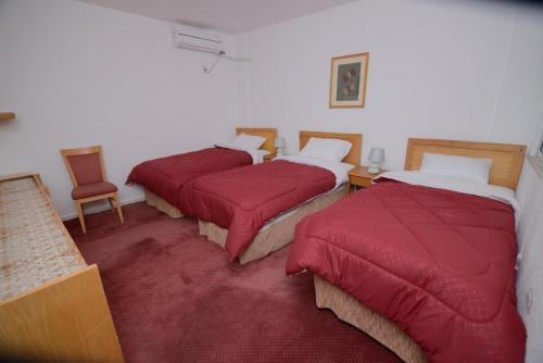 three beds in a room with red covers on them at Petra Lion Hotel in Wadi Musa