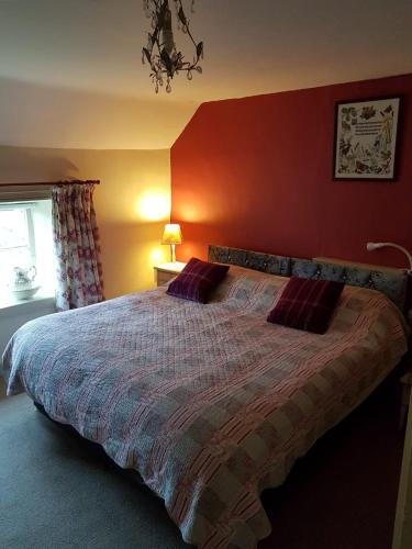 a bedroom with a large bed with a red wall at Manor Farm Bed & Breakfast in Gillamoor