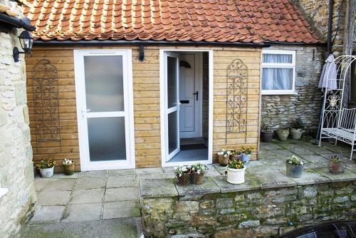 una pequeña casa con una puerta y algunas macetas en Manor Farm Bed & Breakfast en Gillamoor