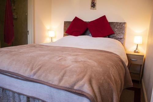 a bedroom with a large bed with red pillows at Manor Farm Bed & Breakfast in Gillamoor