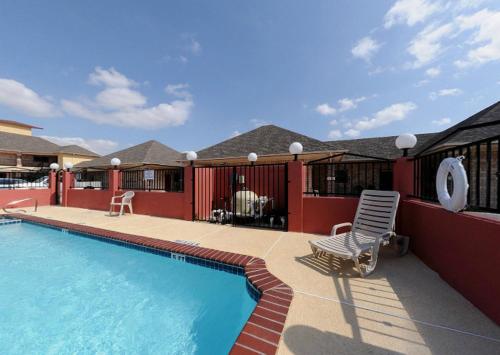 una piscina con una silla junto a una casa en Guest Inn San Benito/Harlingen, en San Benito