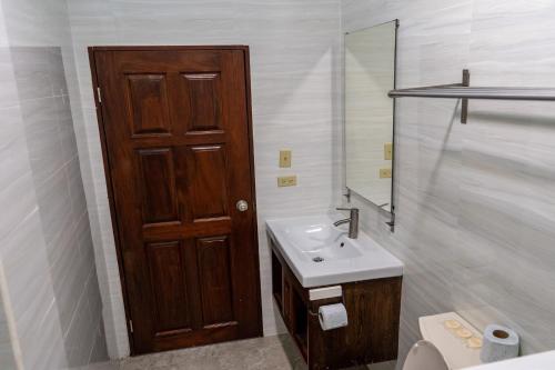 a bathroom with a sink and a wooden door at Island Magic Beach Resort in Caye Caulker