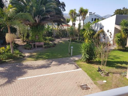 a garden with palm trees and a brick walkway at Bethel B&B / Selfcatering in George
