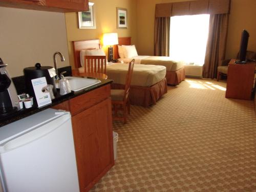 a hotel room with two beds and a kitchen with a sink at Holiday Inn Express Hotel & Suites Chicago West Roselle by IHG in Roselle
