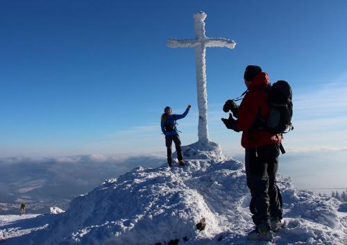 a group of people standing on top of a mountain with a cross at Pension Big Apple in Železná Ruda