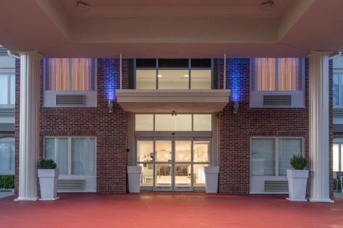 a brick building with glass doors and potted plants at Holiday Inn Express Radcliff Fort Knox by IHG in Radcliff