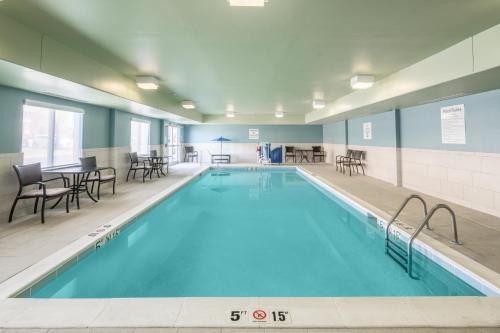 - une piscine avec des chaises et des tables dans un bâtiment dans l'établissement Holiday Inn Express Radcliff Fort Knox, an IHG Hotel, à Radcliff