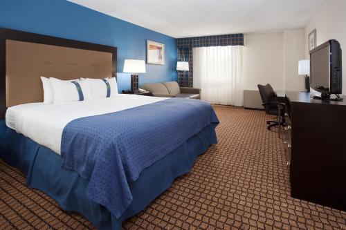 ein Hotelzimmer mit einem großen Bett und einem TV in der Unterkunft Ramada Plaza by Wyndham Sheridan Hotel & Convention Center in Sheridan