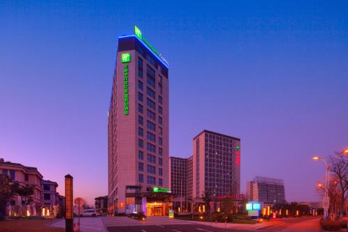 a tall building with a green neon sign on it at Holiday Inn Express Shanghai Jiading Industry Park by IHG in Jiading