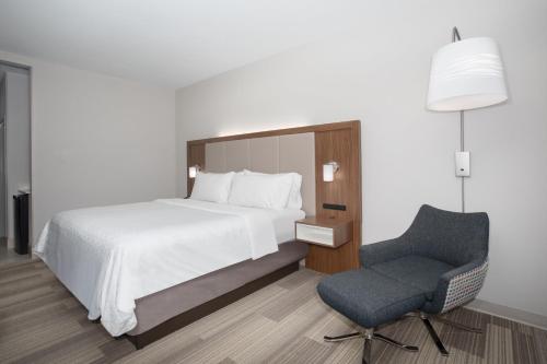 a bedroom with a bed and a chair at Holiday Inn Express Slidell by IHG in Slidell