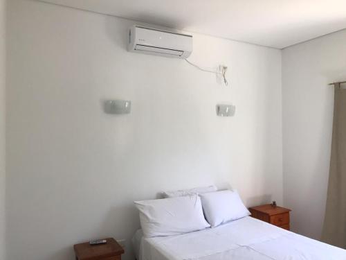 1 dormitorio con 1 cama blanca y aire acondicionado en Cabañas Don Roque in 